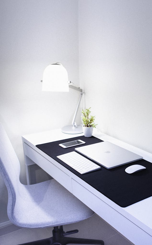 Kunden Startup Sleek, modern home office setup featuring Apple devices, a desk lamp, and a plant.